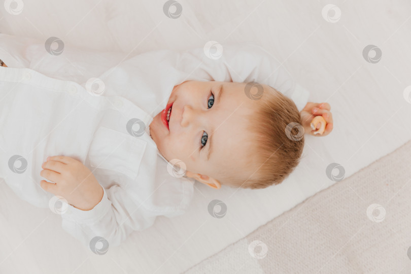 Скачать Портрет милого малыша, лежащего на полу, малыш лежит на полу на одеяле. фотосток Ozero
