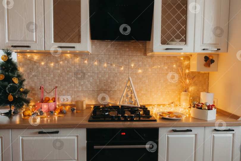 Скачать Интерьер современной кухни с раковиной, шкафчиками в новом элитном доме, оформленном в рождественском стиле. белая кухня. елка на кухне. фотосток Ozero