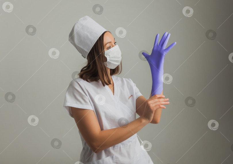 Скачать Красивая женщина-врач или медсестра в защитной маске и резиновых перчатках на светлом фоне с копировальным пространством. Концепция здравоохранения фотосток Ozero