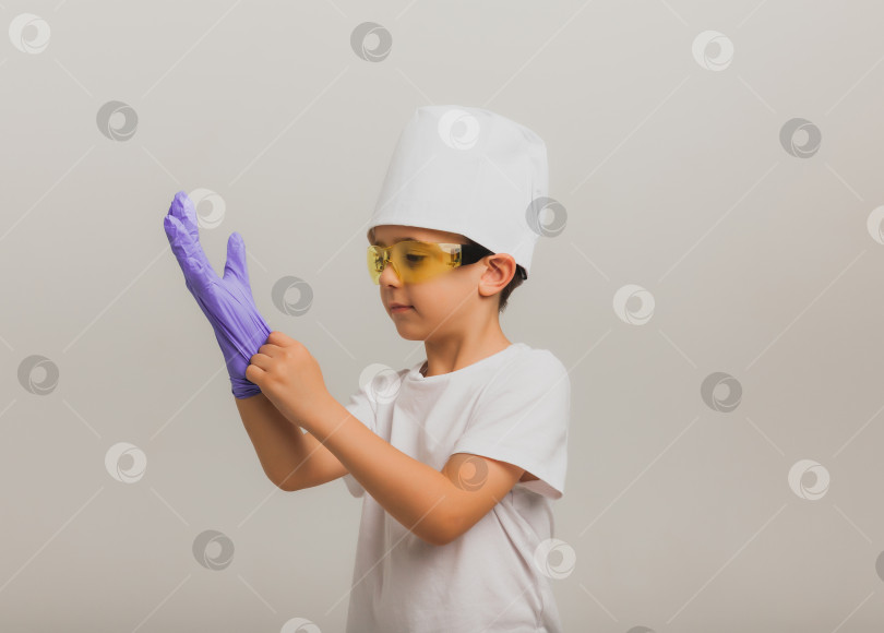 Скачать портрет мальчика в медицинской шапочке и медицинских перчатках с прозрачными очками на светлом фоне. фотосток Ozero