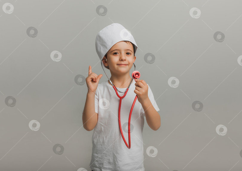 Скачать мальчик в докторской шапочке держит стетоскоп на светлом фоне. маленький доктор. высококачественная студийная фотография фотосток Ozero