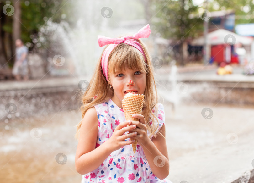 Скачать Портрет милой маленькой девочки-блондинки с мороженым на прогулке в парке. ребенок ест мороженое на открытом воздухе и весело проводит время фотосток Ozero
