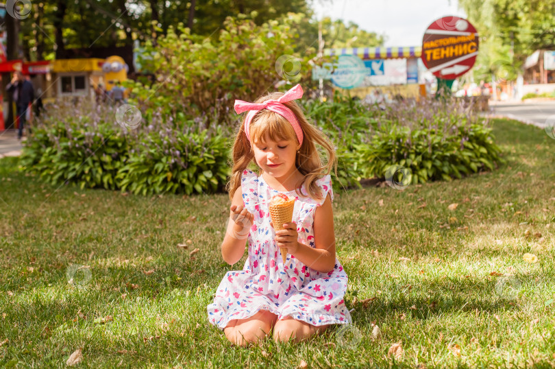 Скачать Портрет милой маленькой девочки-блондинки с мороженым на прогулке в парке. ребенок ест мороженое на открытом воздухе и весело проводит время фотосток Ozero
