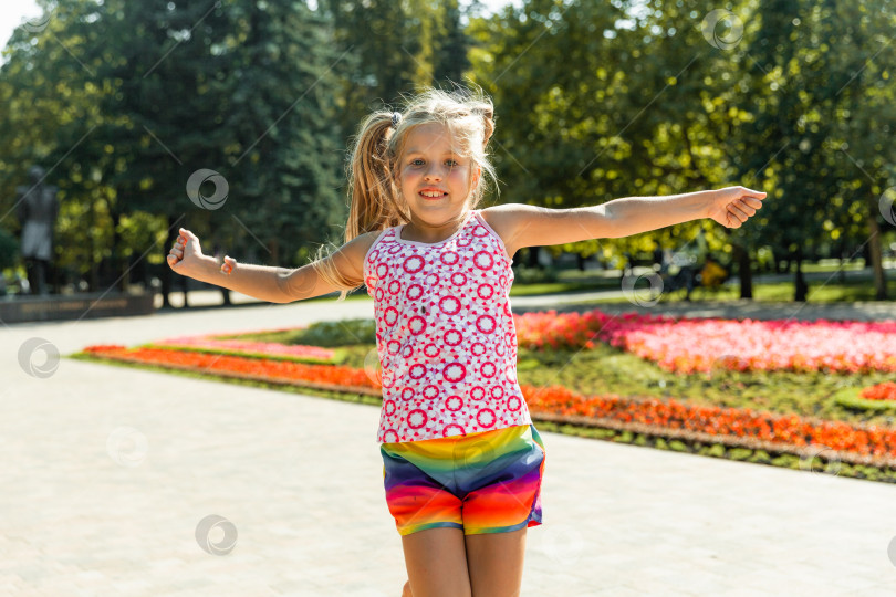 Скачать счастливая маленькая девочка прыгает в парке. маленькая девочка ест мороженое и веселится в городе. фотосток Ozero