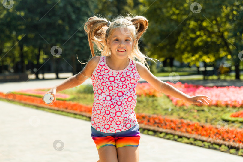 Скачать счастливая маленькая девочка прыгает в парке. маленькая девочка ест мороженое и веселится в городе. фотосток Ozero