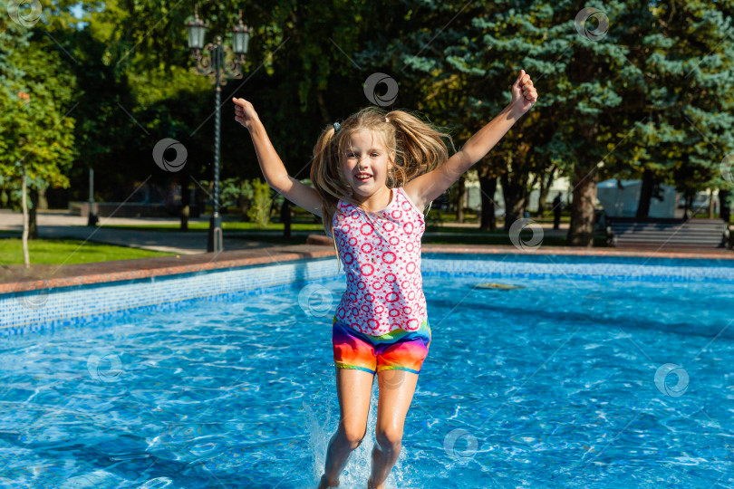 Скачать Милая жизнерадостная маленькая девочка играет в фонтане. Ребенок веселится в летнем парке у городского фонтана. фотосток Ozero