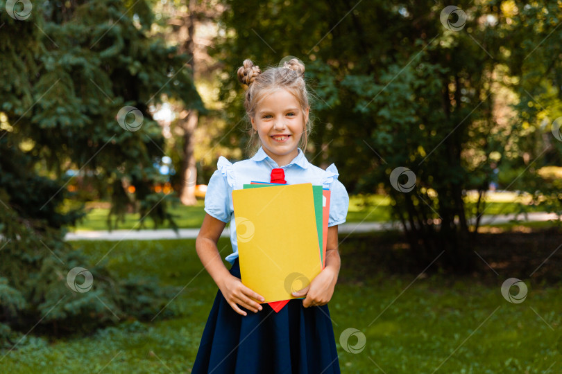 Скачать Счастливая школьница с книгой в руках на открытом воздухе. Маленький ребенок ходит в школу. Пространство для копирования. фотосток Ozero