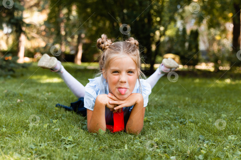 Скачать Портрет маленькой улыбающейся девочки, лежащей на траве. школьница лежит на траве в парке. фотосток Ozero