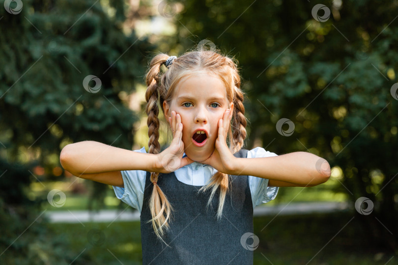 Скачать Портрет молодой взволнованной шокированной улыбающейся девушки, прижимающей руки к лицу. фотосток Ozero
