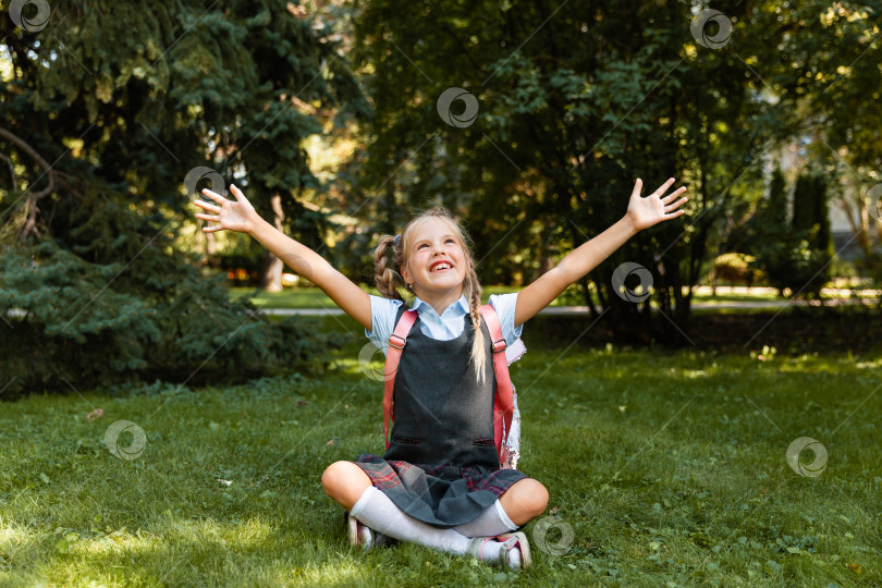 Скачать маленькая школьница в медицинской маске сидит в парке на траве и развлекается. фотосток Ozero