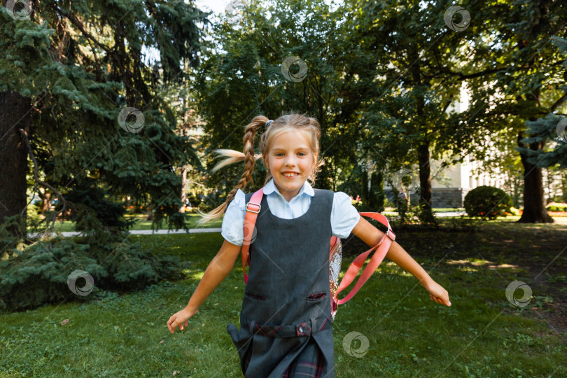 Скачать Красивая маленькая школьница с розовым рюкзачком гуляет по парку и веселится. Школьная форма. фотосток Ozero