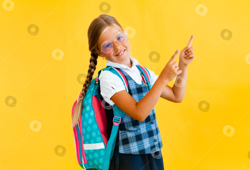 Скачать Портрет улыбающейся маленькой школьницы с рюкзачком и блокнотом в руках на желтом фоне фотосток Ozero