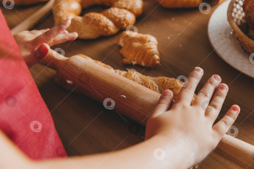 Скачать Счастливая маленькая девочка в форме шеф-повара держит в руках скалку на кухне. Юный шеф-повар. Концепция процесса приготовления фотосток Ozero