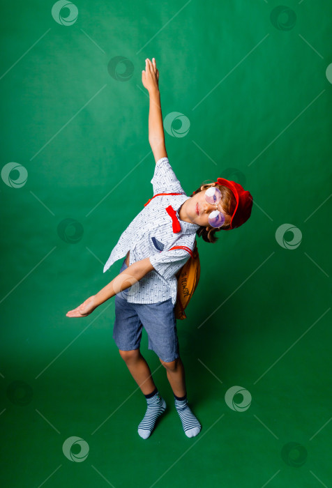 Скачать Мальчик 7 лет стоит на зеленом фоне с распростертыми руками, портрет счастливого ребенка фотосток Ozero