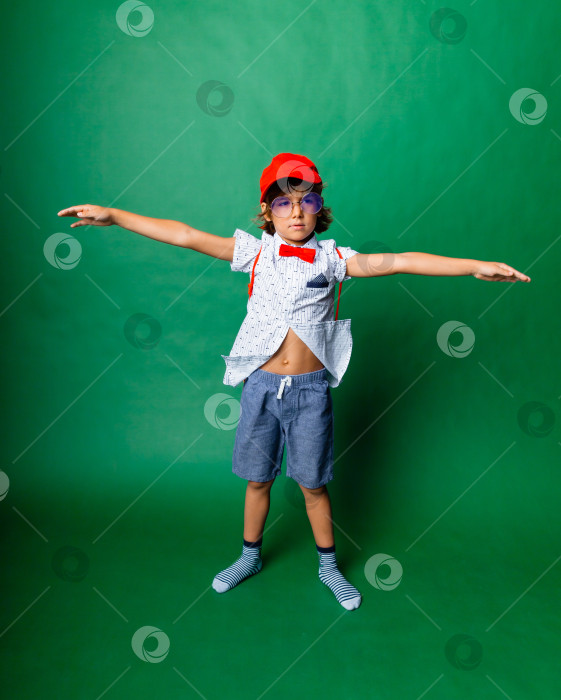 Скачать Мальчик 7 лет стоит на зеленом фоне с распростертыми руками, портрет счастливого ребенка фотосток Ozero