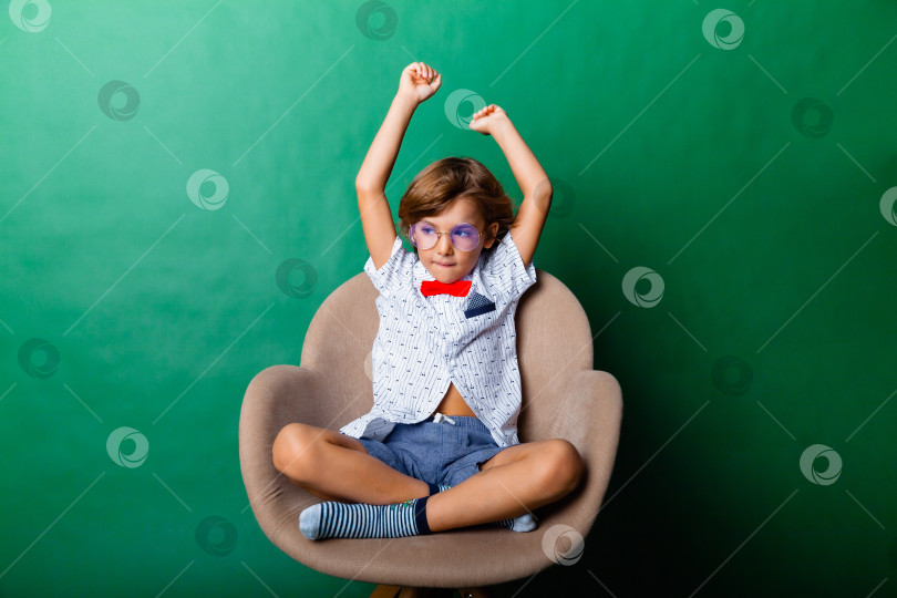 Скачать Жизнерадостный маленький мальчик в полный рост, стоящий с поднятыми руками на сером фоне фотосток Ozero