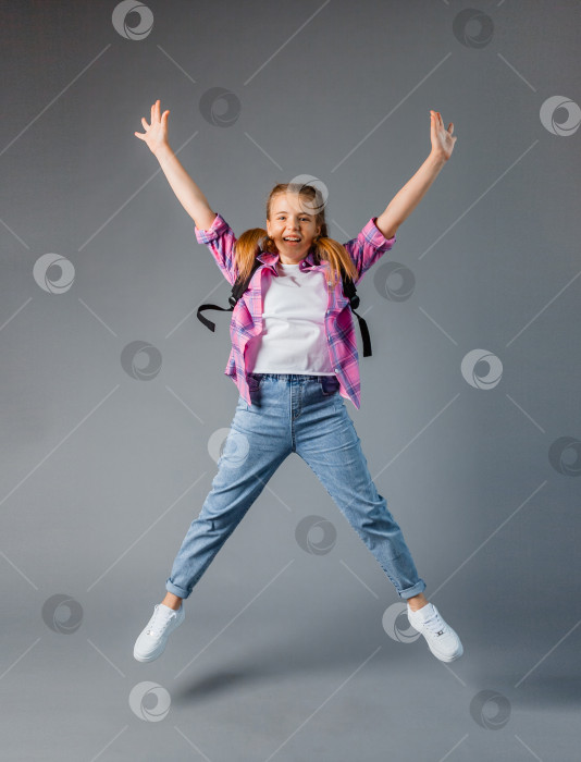 Скачать школьница с рбкзаком прыгает на сером фоне. школьный контент фотосток Ozero