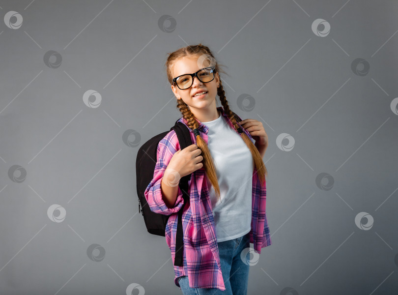 Скачать Подросток с рюкзаком. Симпатичная улыбающаяся школьница. Маленькая девочка-школьница несет рюкзак. Ученица с длинными косами идет в школу. фотосток Ozero