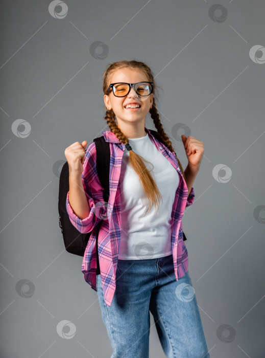 Скачать юная школьница счастливая позитивная с улыбкой радуется победе сжатые в кулаки руки выделены на сером фоне фотосток Ozero