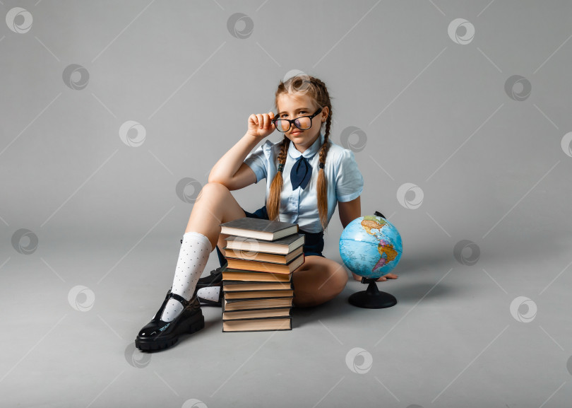 Скачать школьница, изолированная на желтом фоне с глобусом. маленькая девочка в школьной форме сидит на желтом фоне и читает книгу. белокурая девочка в школьной форме на желтом фоне фотосток Ozero