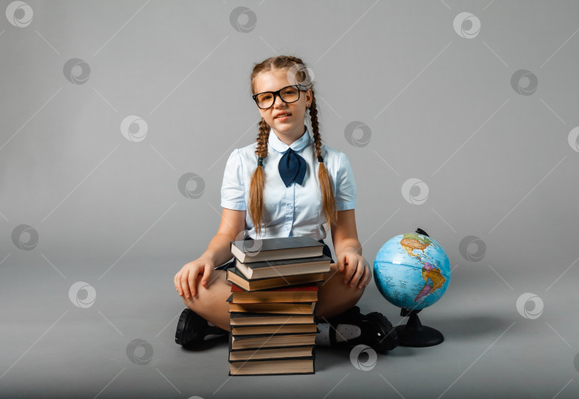 Скачать школьница, изолированная на желтом фоне с глобусом. маленькая девочка в школьной форме сидит на желтом фоне и читает книгу. белокурая девочка в школьной форме на желтом фоне фотосток Ozero