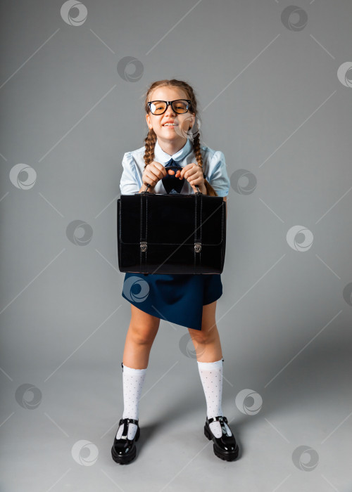 Скачать девочка-подросток в школьной форме с портфелем в руках, выделенная на сером фоне фотосток Ozero
