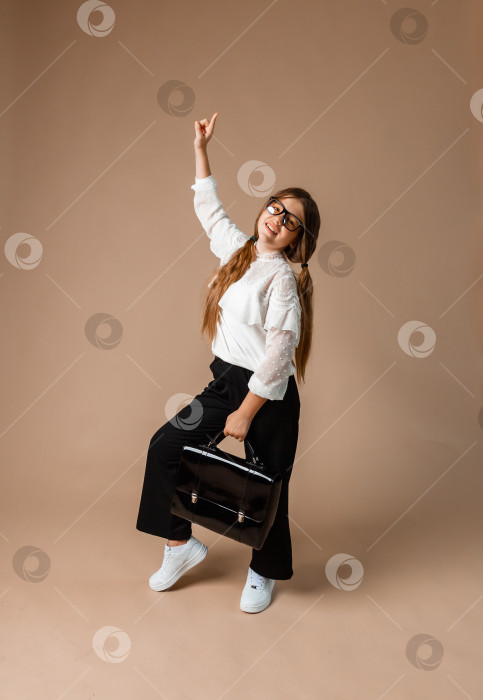 Скачать девочка 12 лет стоит на фоне студии и держит в руках черный портфель фотосток Ozero