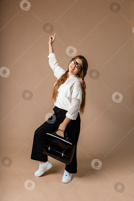 Скачать девочка 12 лет стоит на фоне студии и держит в руках черный портфель фотосток Ozero