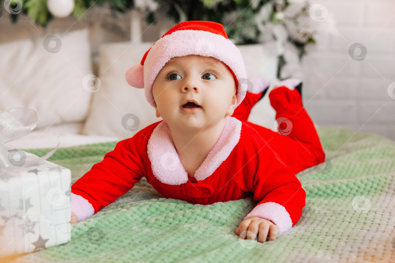Скачать Портрет новорожденного крупным планом. Кавказский малыш 6 месяцев в костюме Санты лежит на вязаном уютном одеяле на кровати. Рождество 2022 года фотосток Ozero