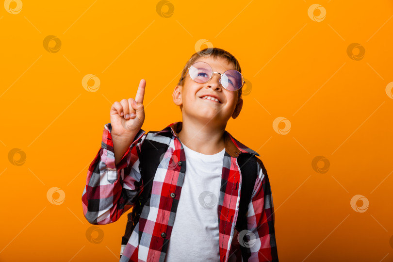 Скачать Крупным планом портрет веселого маленького мальчика-студента, указывающего на отличную идею, на желтом фоне фотосток Ozero
