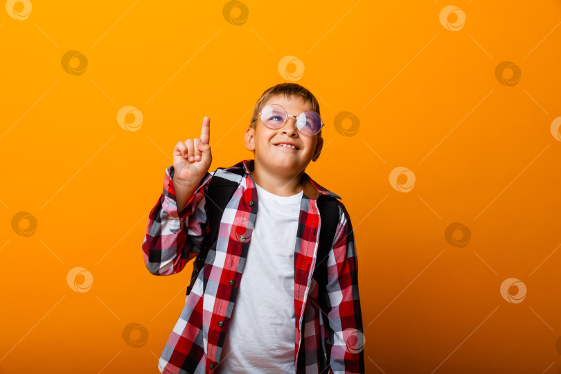 Скачать Крупным планом портрет веселого маленького мальчика-студента, указывающего на отличную идею, на желтом фоне фотосток Ozero