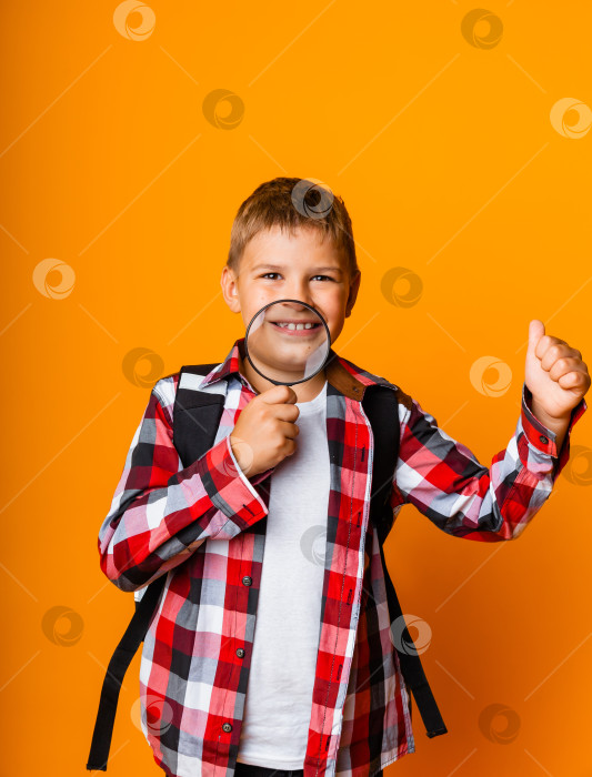 Скачать Мальчик-школьник смотрит через увеличительное стекло, увеличивая свой глаз на желтом фоне фотосток Ozero