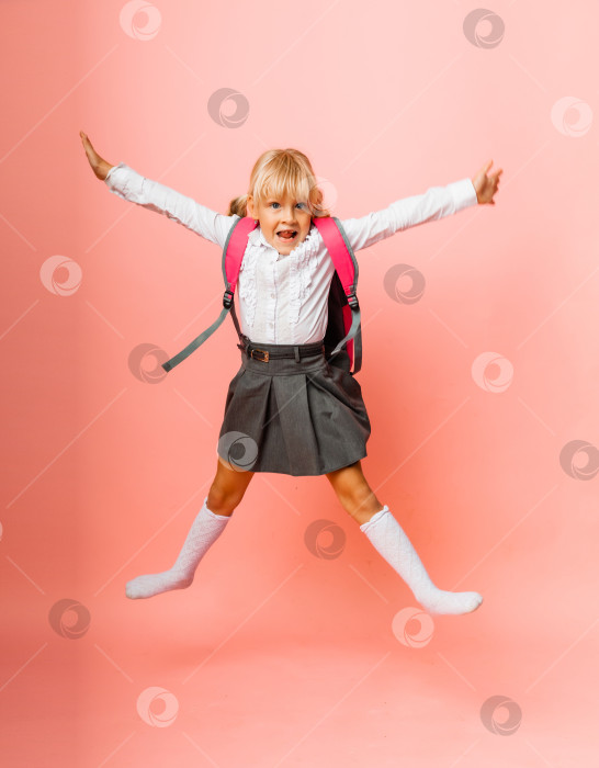 Скачать школьница с рюкзаком прыгает на розовом фоне. фотосток Ozero