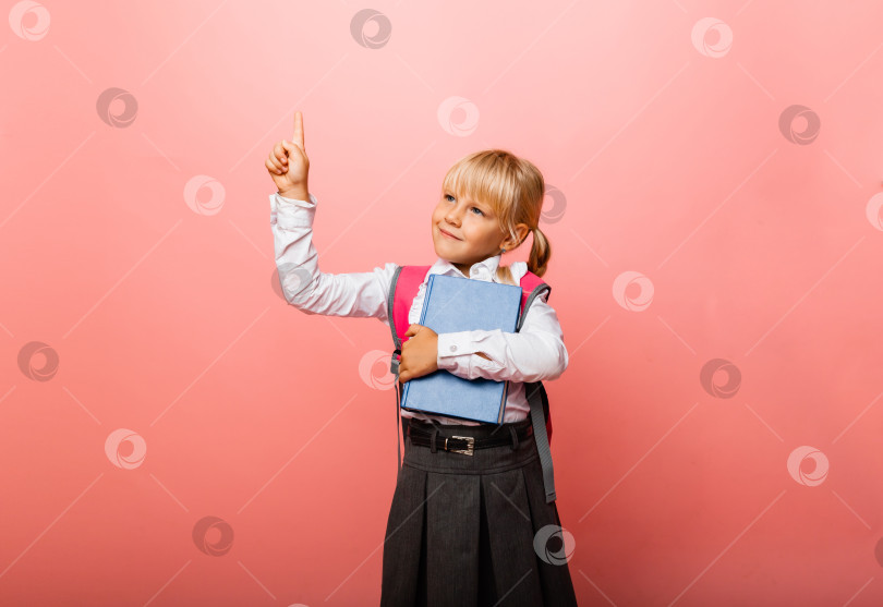 Скачать маленькая школьница на розовом фоне. Ребенок держит учебник и показывает большой палец вверх. Концепция образования. фотосток Ozero