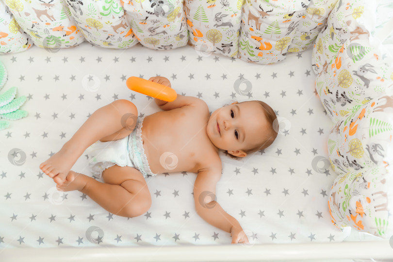 Скачать малышу 11 месяцев. милый малыш в подгузнике лежит и улыбается. фотосток Ozero
