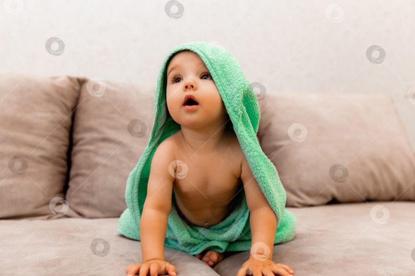 Скачать Симпатичный малыш, завернутый в полотенце, сидит на кровати. ребенок в банном полотенце. фотосток Ozero
