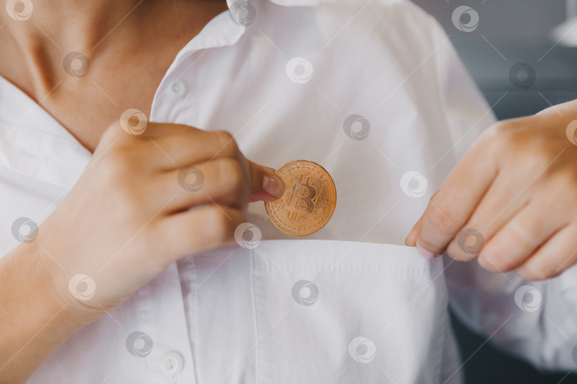 Скачать Крупным планом женщина кладет биткоин в нагрудный карман. виртуальная биткойн-монета. фотосток Ozero
