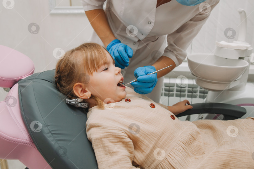 Скачать Стоматолог осматривает зубы ребенка в стоматологическом кресле. концепция медицины и стоматологии. фотосток Ozero
