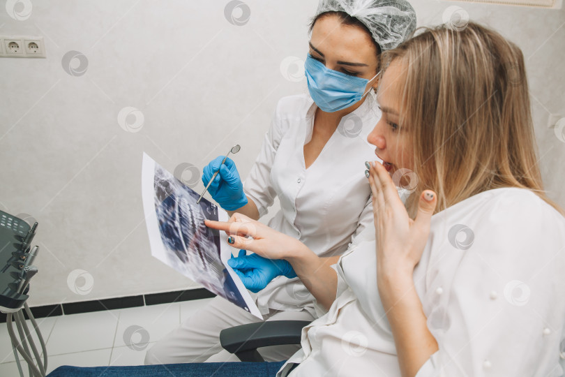 Скачать Стоматолог показывает пациенту рентгеновский снимок. Компьютерная диагностика. стоматологическая томография фотосток Ozero