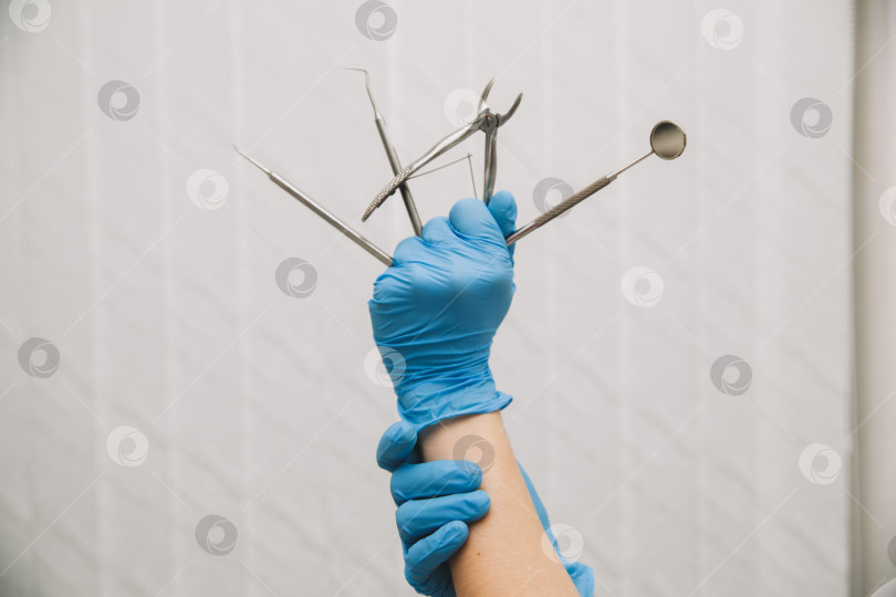 Скачать дантист держит в руках стоматологические инструменты, одетый в синие перчатки, крупным планом. лечение зубов фотосток Ozero