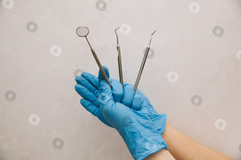 Скачать дантист держит в руках стоматологические инструменты, одетый в синие перчатки, крупным планом. лечение зубов фотосток Ozero
