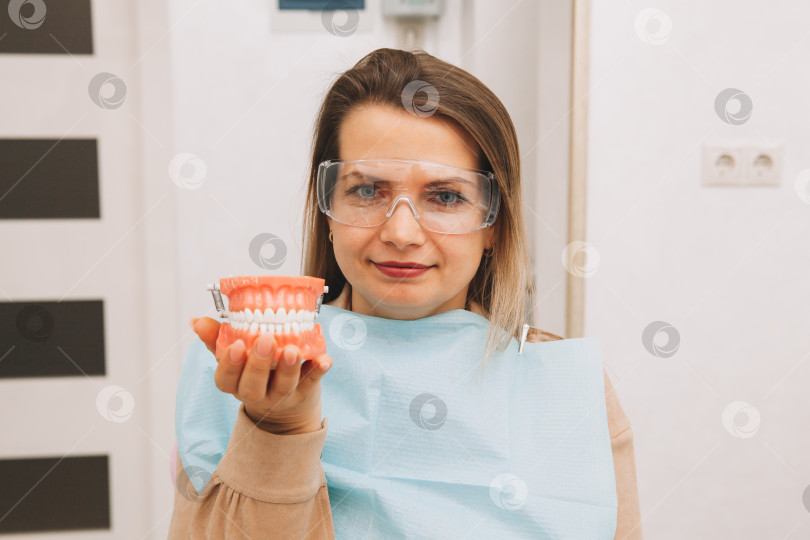 Скачать Женщина держит в руках образец зуба или зубной протез у стоматолога. концепция медицины и стоматологии. фотосток Ozero