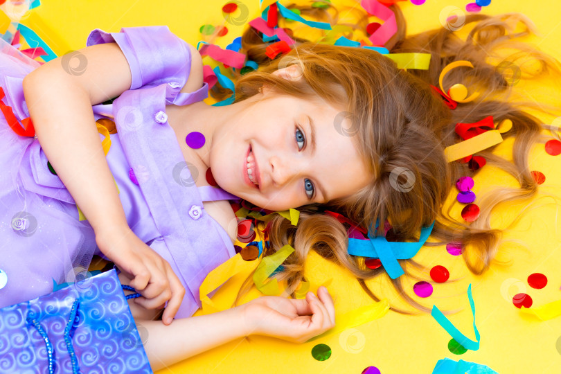 Скачать Счастливая маленькая девочка в голубом платье празднует вечеринку с конфетти, вид сверху. День рождения ребенка, положительные эмоции. фотосток Ozero