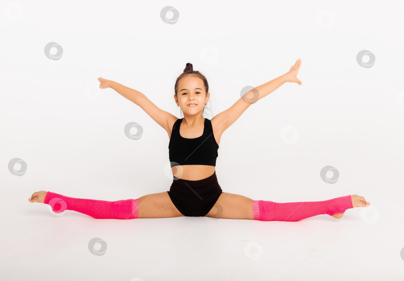 Скачать Маленькая гимнастка на большом белом кубе выполняет спортивные упражнения фотосток Ozero
