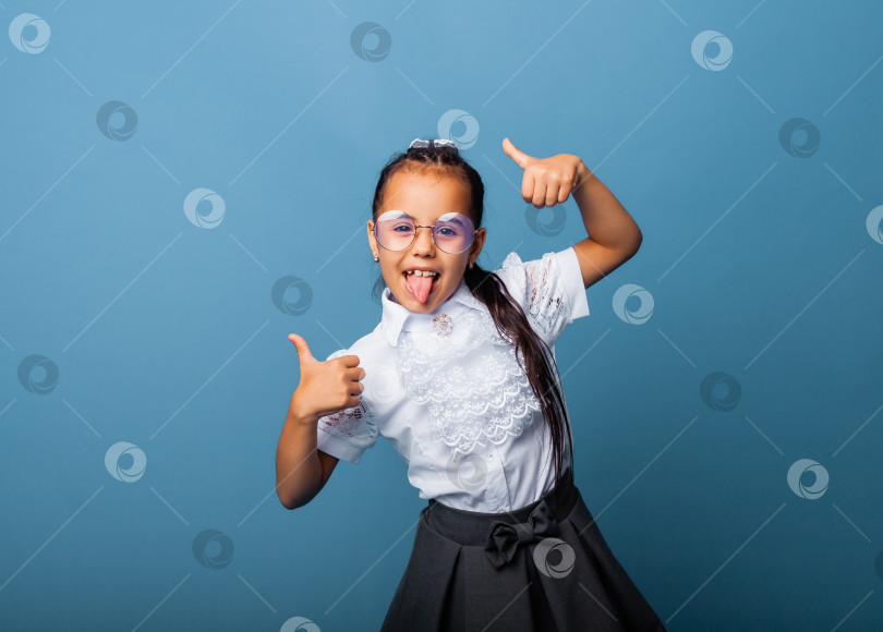 Скачать Симпатичная школьница, которая классно улыбается и смотрит в камеру. синий фон и боковое пространство. фотосток Ozero