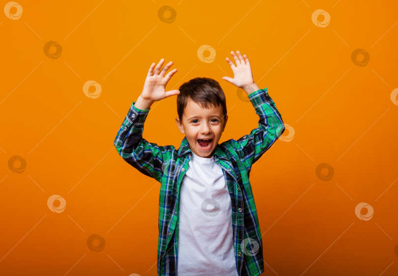 Скачать Красивый мальчик показывает язык и веселится на желтом фоне. Кавказский эмоциональный мальчик. фотосток Ozero