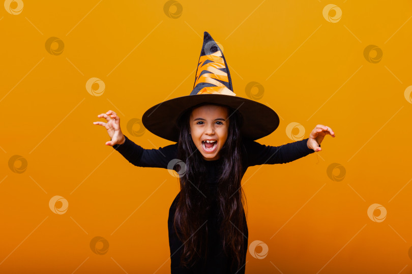Скачать Портрет сердитой маленькой девочки в костюме ведьмы на желтом фоне. хэллоуин. фотосток Ozero