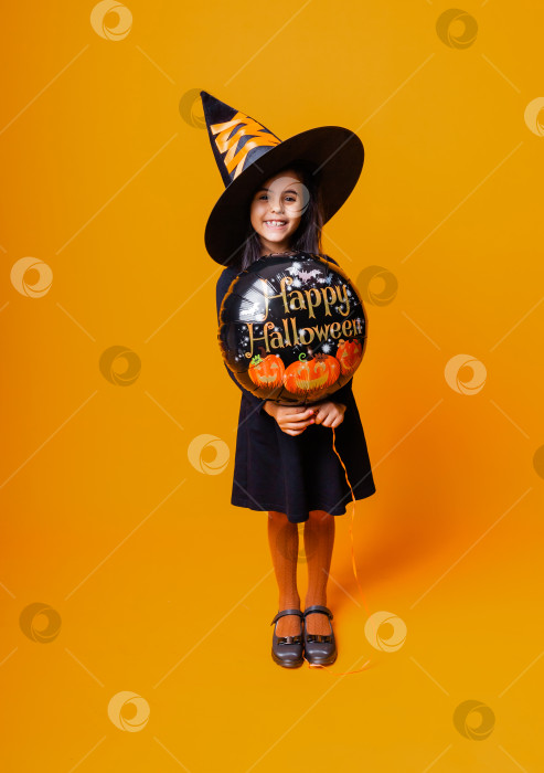 Скачать Веселая девушка в костюме ведьмы держит в руках воздушный шар с надписью Halloween. концепция Хэллоуина. фотосток Ozero