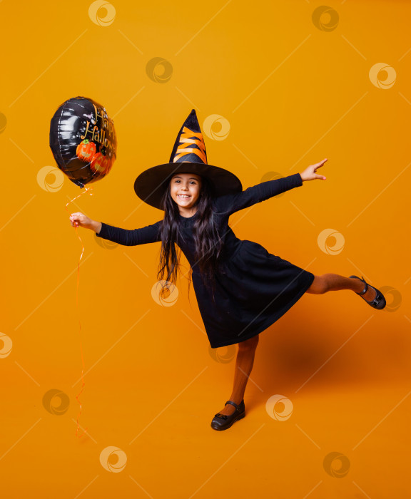 Скачать Веселая девушка в костюме ведьмы держит в руках воздушный шар с надписью Halloween. концепция Хэллоуина. фотосток Ozero