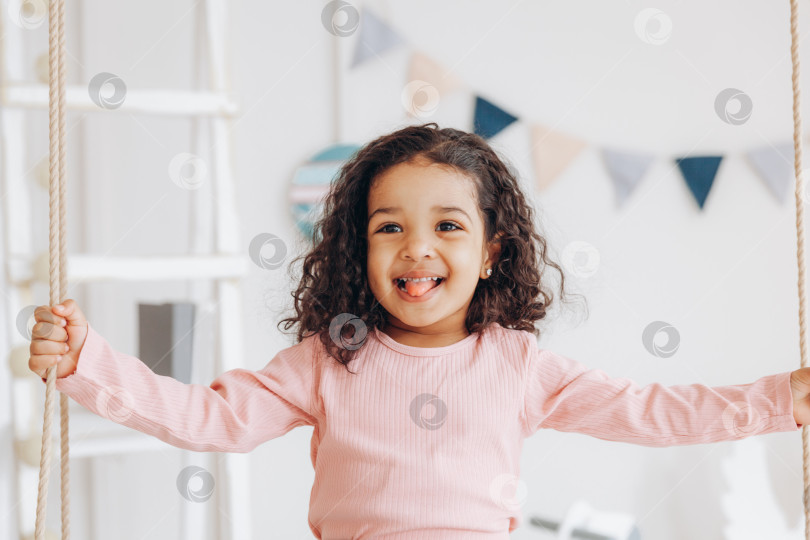 Скачать маленькая темнокожая девочка катается на качелях. дизайн интерьера детской комнаты фотосток Ozero